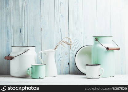 Enamelware on the kitchen table over blue wooden wall. Enamelware still life