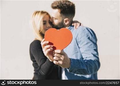 enamored couple posing with red heart