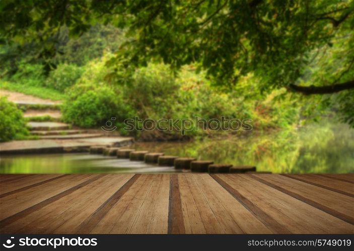 Enchanted forest scene of slow flowing stream with vibrant reflections with wooden planks floor