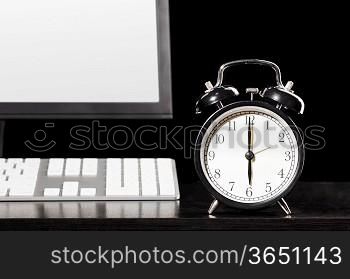 end of working day. office computer with clock on black background