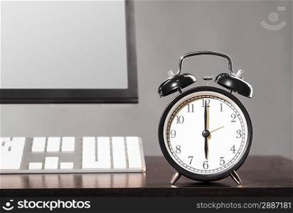 end of working day. office computer with clock on gray background