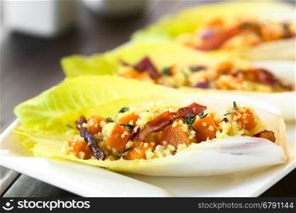 Endive leaves filled with a salad of couscous, pumpkin, red onion and bacon, sprinkled with fresh thyme leaves, photographed with natural light (Selective Focus, Focus one third into the image)