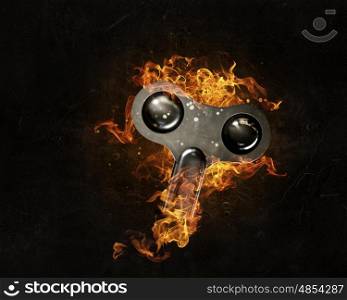 Endless energy concept. Wound key in fire flames on dark background