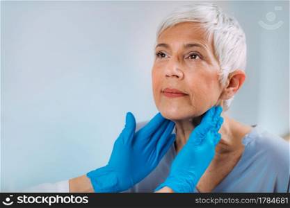 Endocrinology doctor examining a senior woman with thyroid gland disease symptoms. Doctor Examining a Senior Woman with Thyroid Gland Disease Symptoms