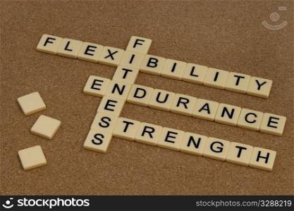 endurance, flexibility, strength - fitness training goals concept, crossword with ivory letter blocks on cork bulleting board
