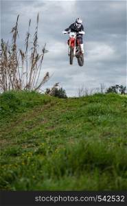 Enduro bike rider in action. Jump on mud and grass terrain.