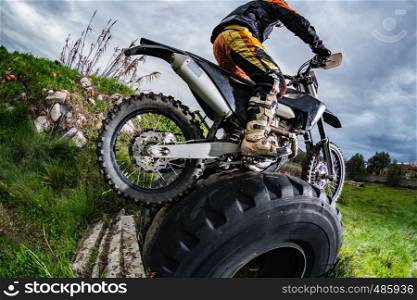 Enduro bike rider in action. Obstacle overcome on mud and grass terrain.
