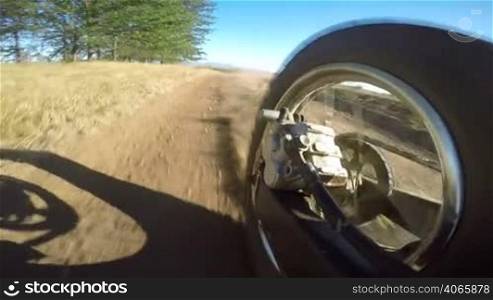 Enduro racer riding bike on dirt track kicking up dust rear wheel point of view