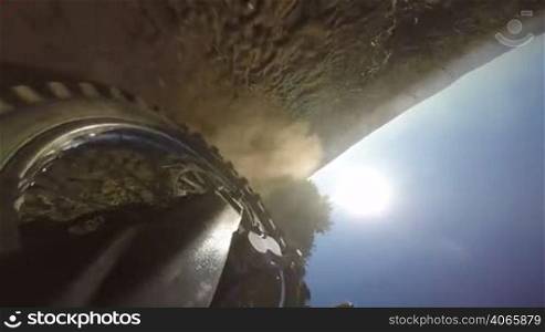 Enduro racer riding bike on dirt track kicking up dust rear wheel point of view