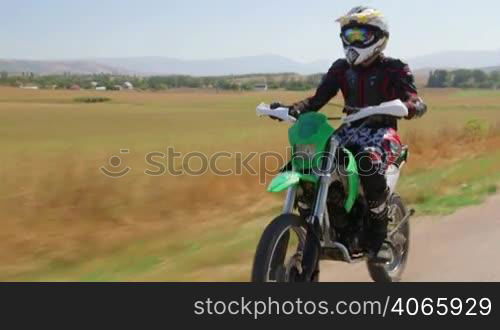 Enduro racer riding dirt bike, front side view vehicle shot