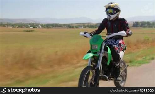 Enduro racer riding dirt bike, front side view vehicle shot