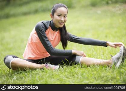 Energetic young woman exercising on the lawn