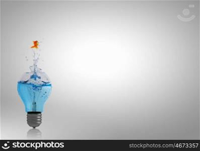 Energy change concept. Goldfish jumping of light bulb filled with water