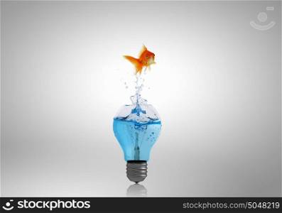 Energy change concept. Goldfish jumping of light bulb filled with water