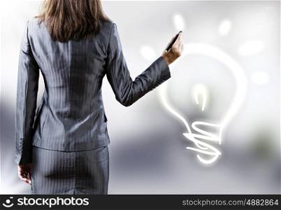 Energy concept. Rear view of businesswoman touching light bulb