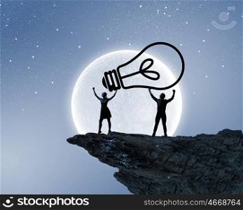 Energy concept. Silhouettes of young couple at night holding bulb