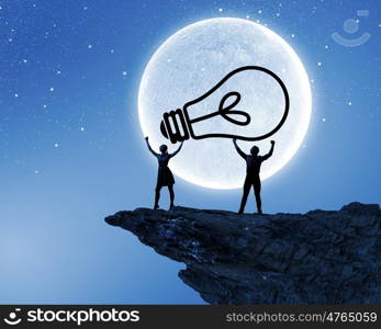 Energy concept. Silhouettes of young couple at night holding bulb