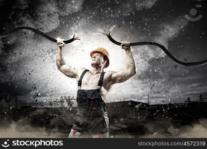 Energy concept. Strong man in uniform tearing electricity cable with hands