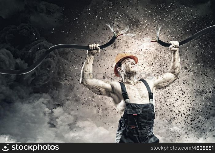 Energy concept. Strong man in uniform tearing electricity cable with hands