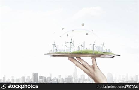 Energy generators on tray. Hand holding metal tray with wind energy concept
