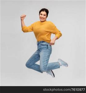 energy, motion people concept - happy smiling young woman with pierced nose jumping over grey background. happy young woman with pierced nose jumping