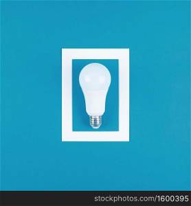 Energy-saving and eco-friendly life in conceptual frame. Creative top view flat lay of LED light bulb composition with copy space on blue background in minimal style.
