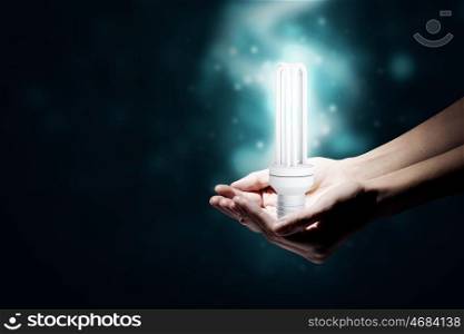 Energy saving. Close up of hand holding glowing light bulb