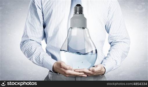 Energy saving concept. Close up of businessman holding light bulb filled with water