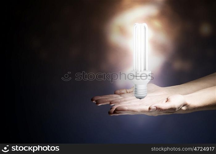 Energy saving concept. Close up of hand holding glowing light bulb