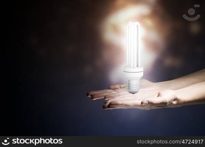 Energy saving concept. Close up of hand holding glowing light bulb