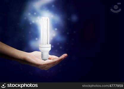 Energy saving concept. Close up of hand holding glowing light bulb