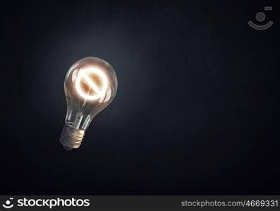 Energy saving. Glass glowing light bulb with prohibition sign inside