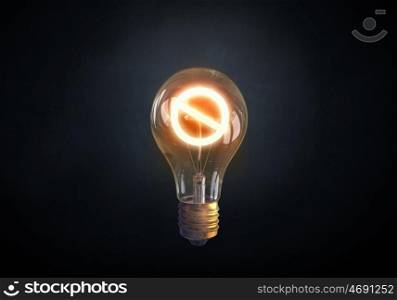 Energy saving. Glass glowing light bulb with prohibition sign inside