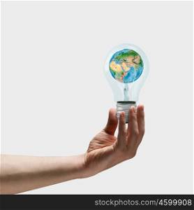 Energy saving. Image of human hand holding bulb with earth planet inside. Elements of this image are furnished by NASA