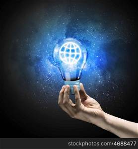 Energy saving. Image of human hand holding bulb with earth planet inside