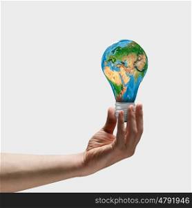 Energy saving. Image of human hand holding bulb with earth planet inside. Elements of this image are furnished by NASA
