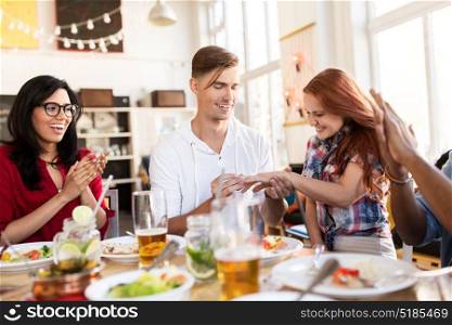 engagement and people concept - happy man doing proposal to his girlfriend and giving her diamond ring at restaurant. happy man doing proposal to woman at restaurant