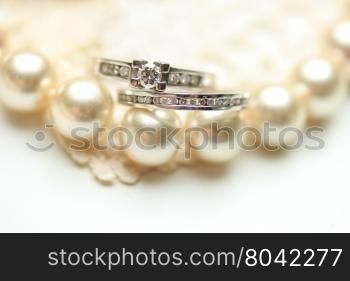 Engagement ring and wedding band with diamonds on a pearl necklace