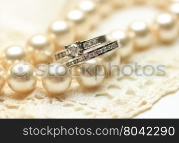 Engagement ring and wedding band with diamonds on a pearl necklace