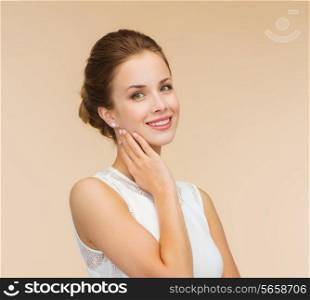 engagenment, celebration, wedding and happiness concept - smiling woman in white dress wearing diamond ring over beige background