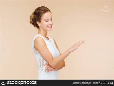 engagenment, celebration, wedding and happiness concept - smiling woman in white dress wearing diamond ring over beige background