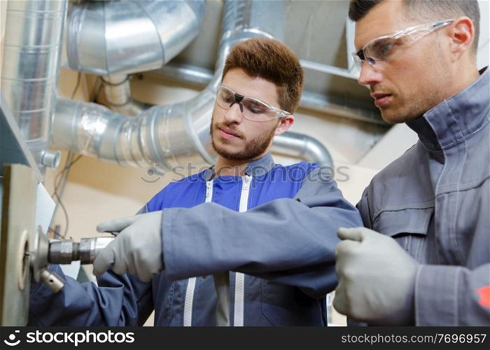 engineer advising apprentice in factory front view close up