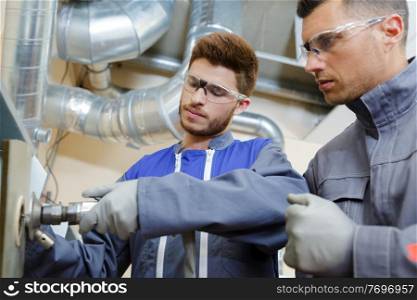engineer advising apprentice in factory front view close up