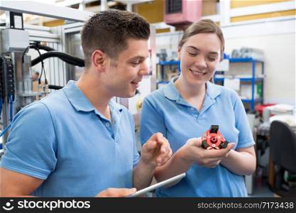 Engineer And Apprentice Examining Component In Factory