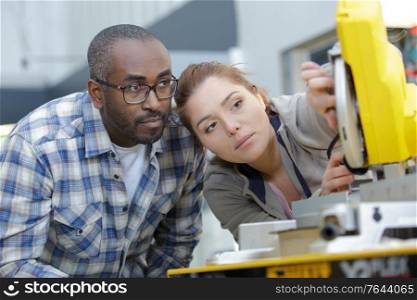 engineer and apprentice examining component in factory