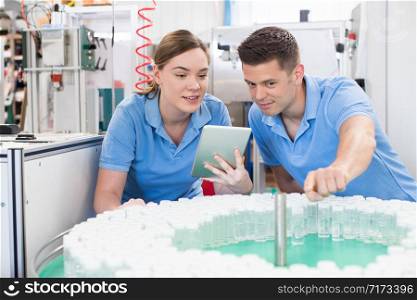 Engineer And Apprentice With Digital Tablet Working In Bottle Capping Factory