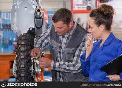 engineer and apprentice working on machine in factory