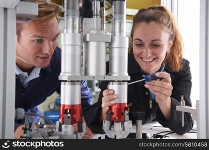 Engineer And Apprentice Working On Machine In Factory