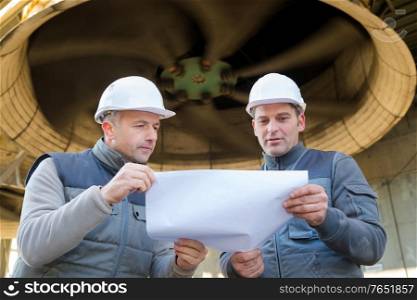 engineer and foreman pointing to drawing paper