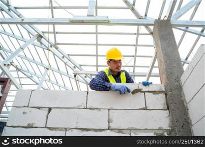 Engineer applying putty or tile glue to with lightweight concrete blocks,On construction site.